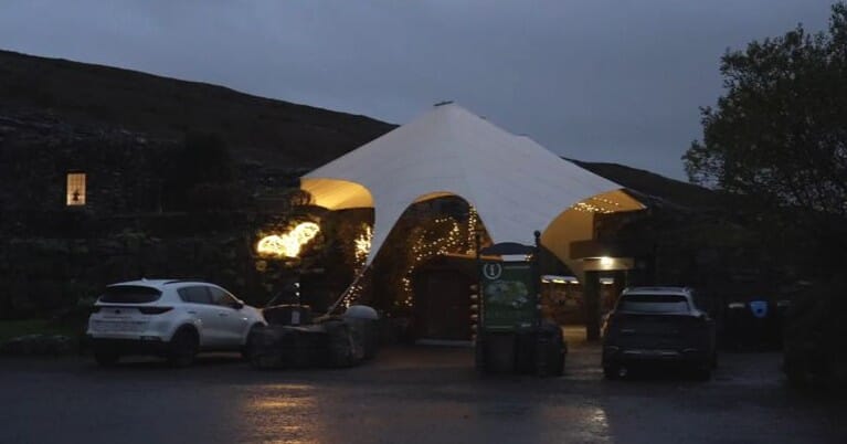 A tent and bat neon light and the entrance to a cave 
