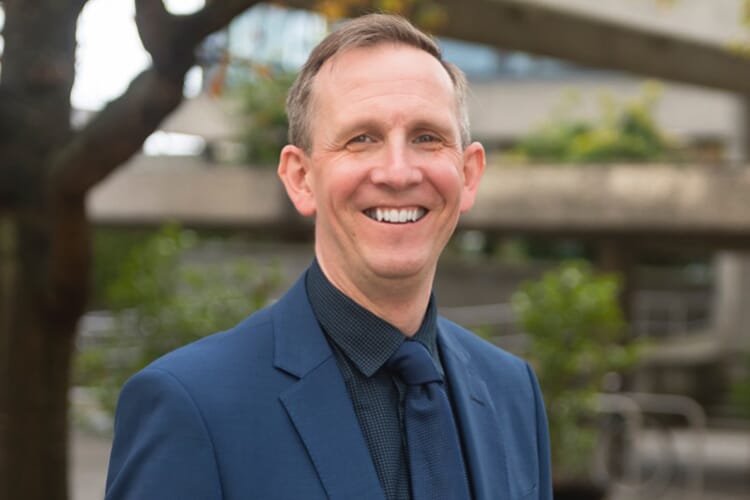 Man in a navy suit smiling at the camera